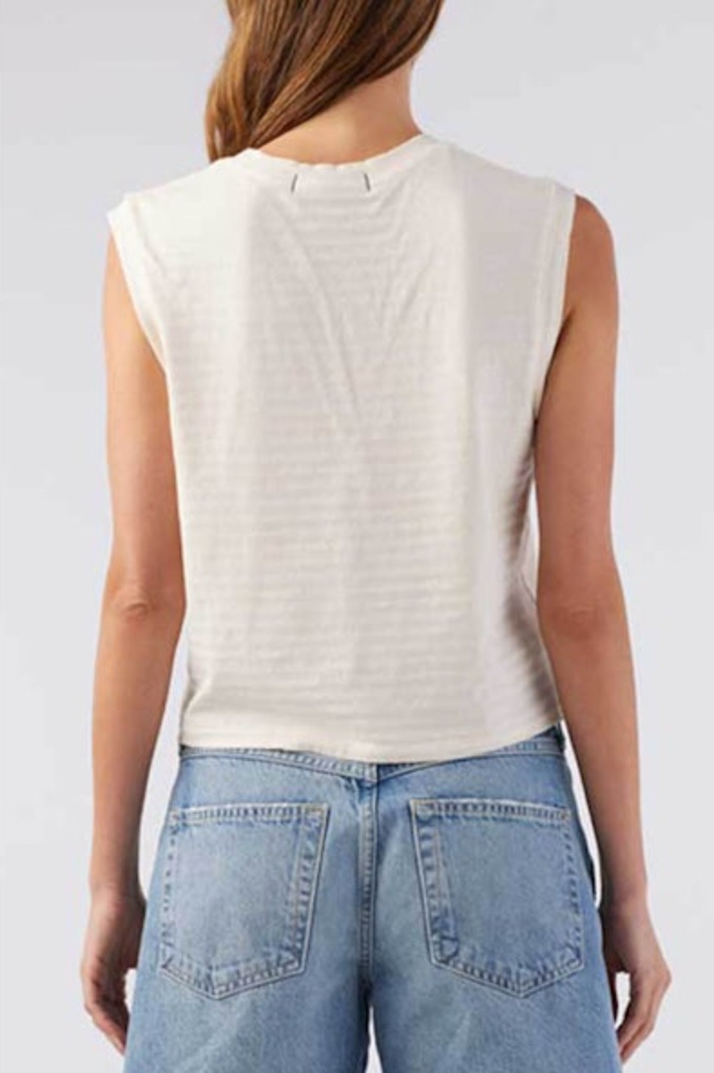 Image of model wearing AMO Denim Babe Sleeveless Cropped Tee in Natural White. Babe Tee is a muscle style sleeveless tee with a crew neck and cropped length. Designed and produced in Los Angeles.