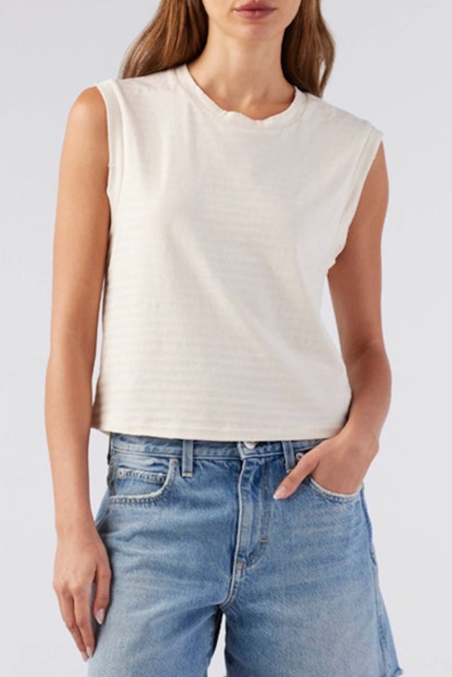 Image of model wearing AMO Denim Babe Sleeveless Cropped Tee in Natural White. Babe Tee is a muscle style sleeveless tee with a crew neck and cropped length. Designed and produced in Los Angeles.