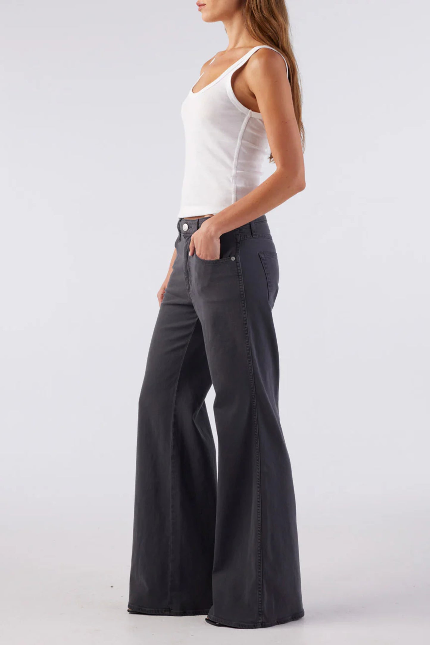 Image of model wearing AMO Denim Elizabeth Flare Jean in Pewter Black. Elizabeth Flare is a Premium Mid-Rise Denim with a Bell Bottom Flare Leg Opening. Made in Los Angeles from Eco-Friendly Cotton-Lyocell Denim.