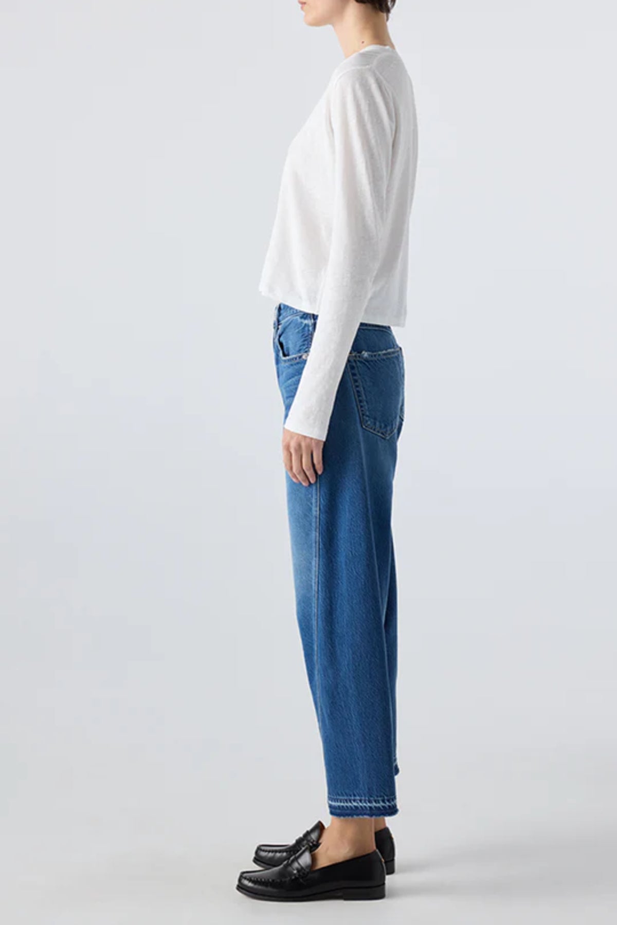 Image of model wearing AMO Denim Maria Barrel Jean in Long Weekend Wash. Maria is a cropped, raw hem Jean with a twisted seam giving a barrel leg silhouette. Made in USA.