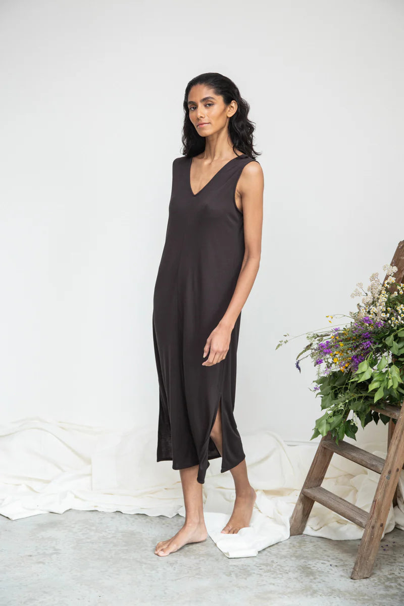 Image of model wearing Beaumont Organic Catalina Lou Column Dress in Charcoal Lyocell. Catalina Dress has a v-neck front and v-back with a midi length and symmetrical side slits; optional waist sash. Ethically made in Portugal.