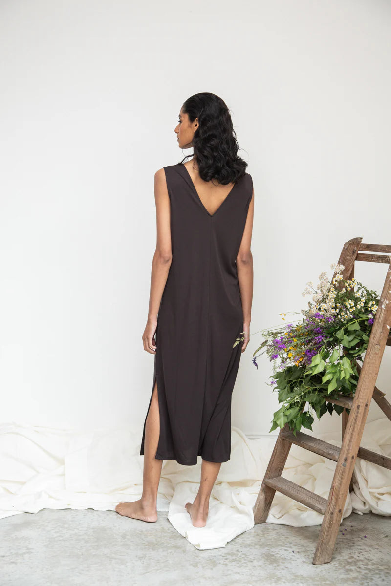 Image of model wearing Beaumont Organic Catalina Lou Column Dress in Charcoal Lyocell. Catalina Dress has a v-neck front and v-back with a midi length and symmetrical side slits; optional waist sash. Ethically made in Portugal.