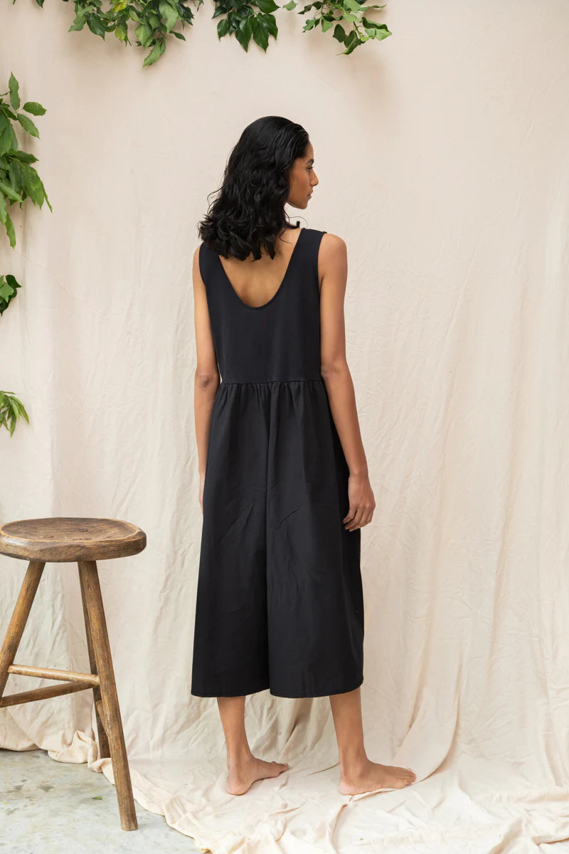 Image of model wearing Beaumont Organic Rory Coton Jumpsuit in black. Rory is a pull on style sleeveless jumpsuit with a scoop neck, relaxed waistline, and wide culotte style leg opening. Cropped fit. Ethically made in Portugal from organic cotton.