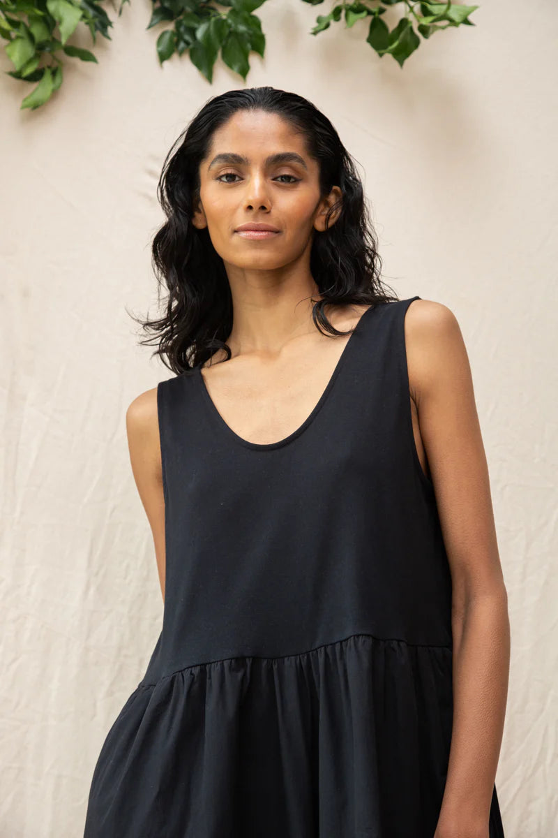 Image of model wearing Beaumont Organic Rory Coton Jumpsuit in black. Rory is a pull on style sleeveless jumpsuit with a scoop neck, relaxed waistline, and wide culotte style leg opening. Cropped fit. Ethically made in Portugal from organic cotton.
