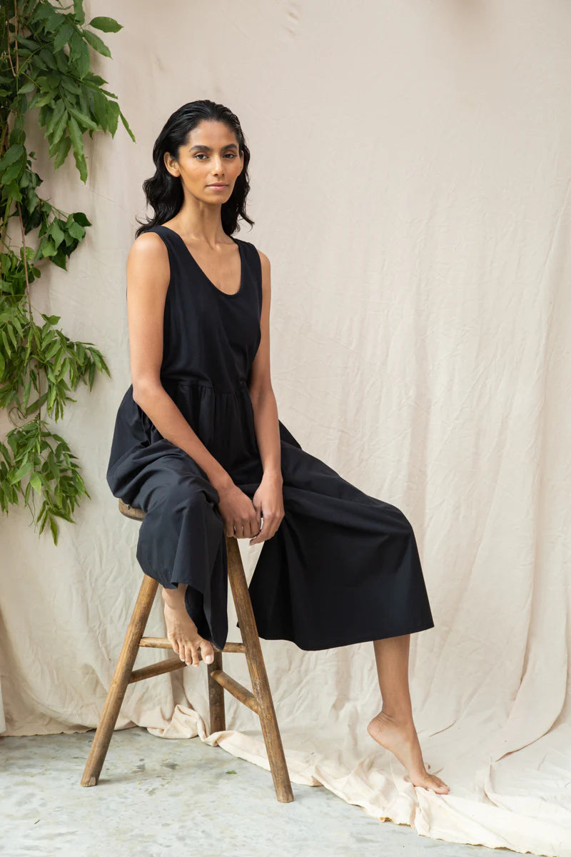 Image of model wearing Beaumont Organic Rory Coton Jumpsuit in black. Rory is a pull on style sleeveless jumpsuit with a scoop neck, relaxed waistline, and wide culotte style leg opening. Cropped fit. Ethically made in Portugal from organic cotton.
