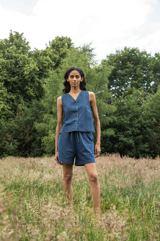 Image of model wearing Beaumont Organic Jovie Leigh Denim Vest. Jovie Leigh features a swinging body, pleated undersleeve, and two tonal buttons on front. Ethically made in Portugal from organic cotton denim.