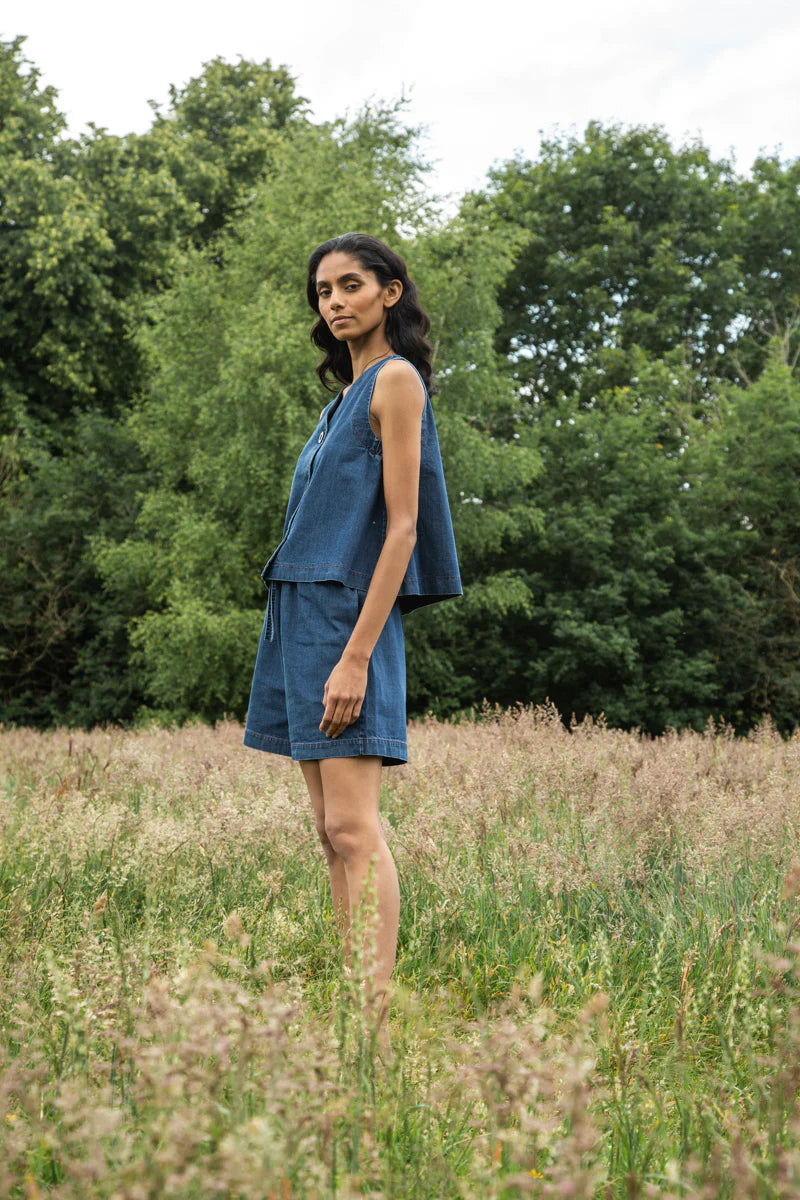 Image of model wearing Beaumont Organic Jovie Leigh Denim Vest. Jovie Leigh features a swinging body, pleated undersleeve, and two tonal buttons on front. Ethically made in Portugal from organic cotton denim.