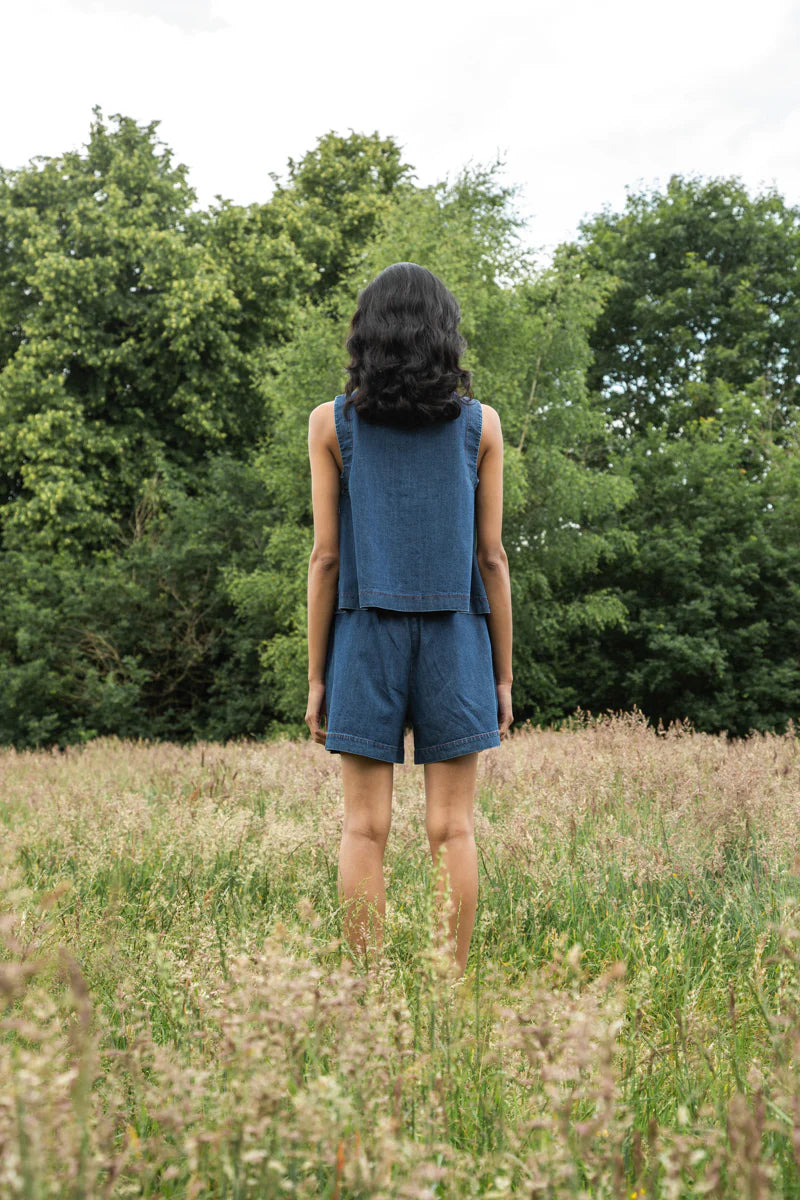 Image of model wearing Beaumont Organic Jovie Leigh Denim Vest. Jovie Leigh features a swinging body, pleated undersleeve, and two tonal buttons on front. Ethically made in Portugal from organic cotton denim.