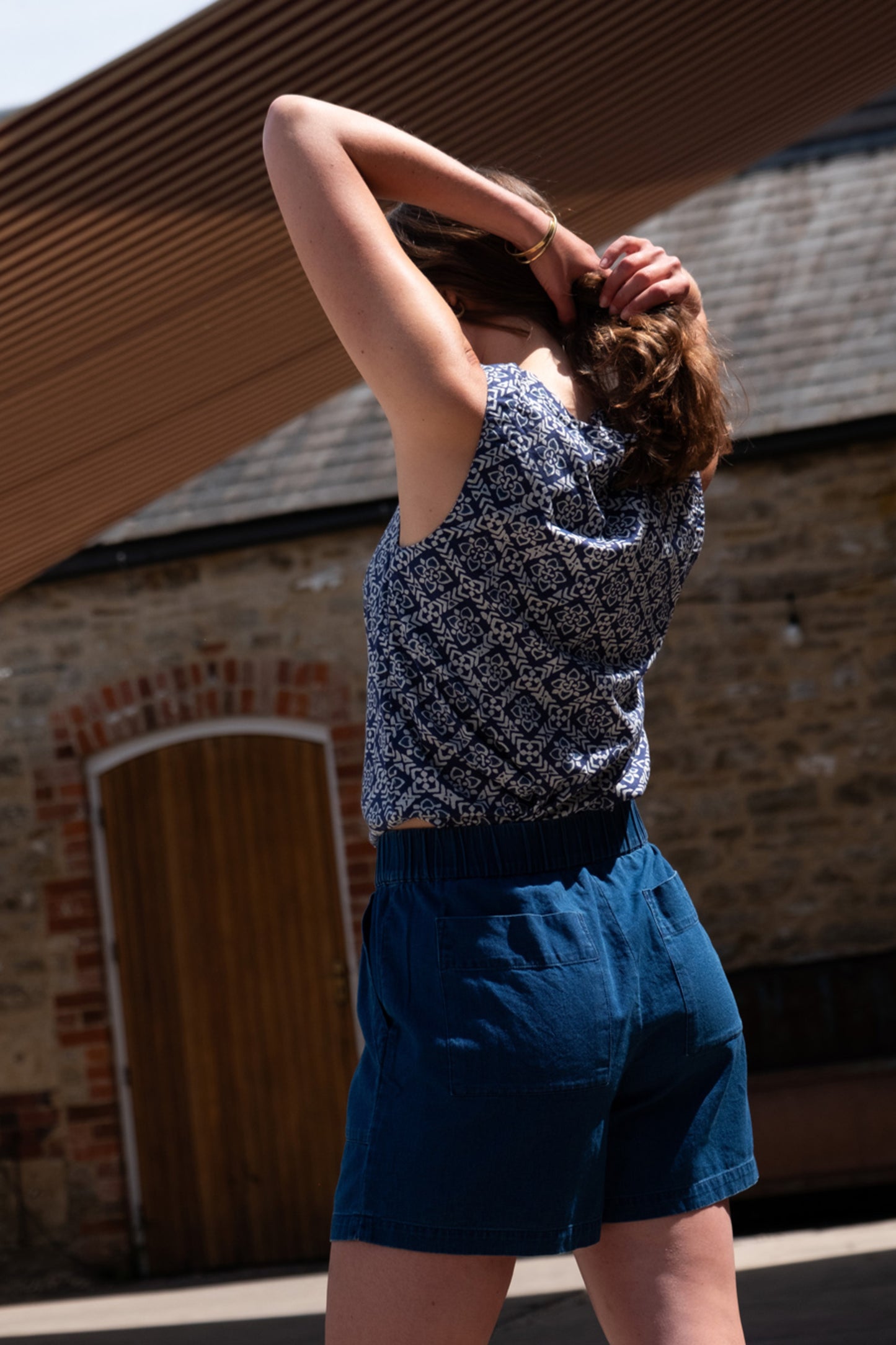 Image of model wearing BIBICO Pippa Sleeveless Top in Indigo Block Print. Pippa Top is a crew neck, medium length, sleeveless shell top. Made by Fair Trade Certified Producers using Hand Block Printed Organic Cotton Fabric.