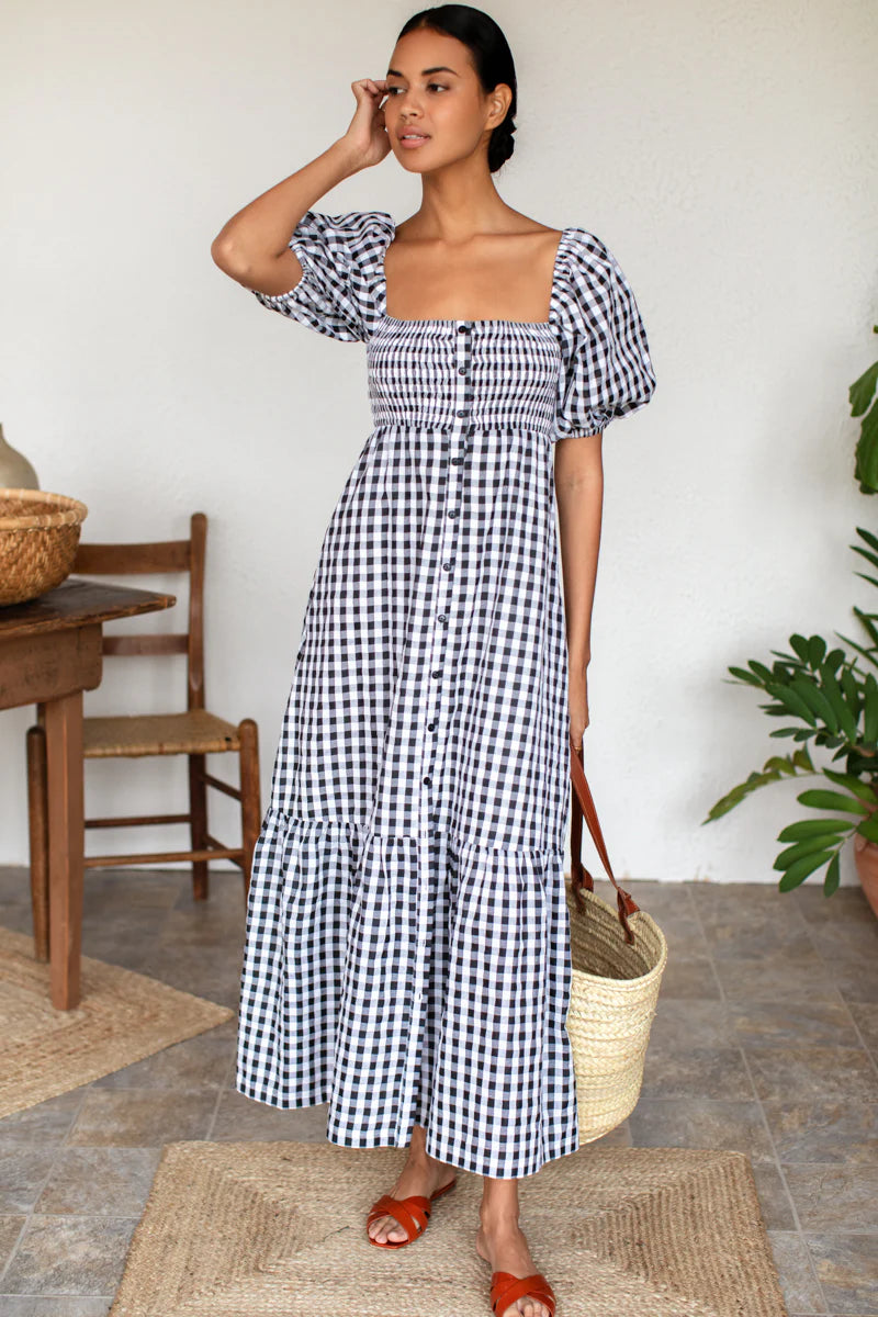 Image of model wearing Emerson Fry Love Tomas Santiago Maxi Dress in Black + White Gingham Check. Santiago dress has a square neckline, shirred bodice, short puff sleeve, and full length skirt with button front closure.