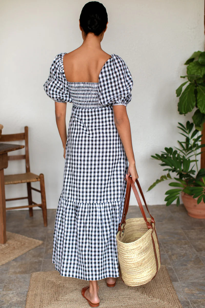 Image of model wearing Emerson Fry Love Tomas Santiago Maxi Dress in Black + White Gingham Check. Santiago dress has a square neckline, shirred bodice, short puff sleeve, and full length skirt with button front closure.
