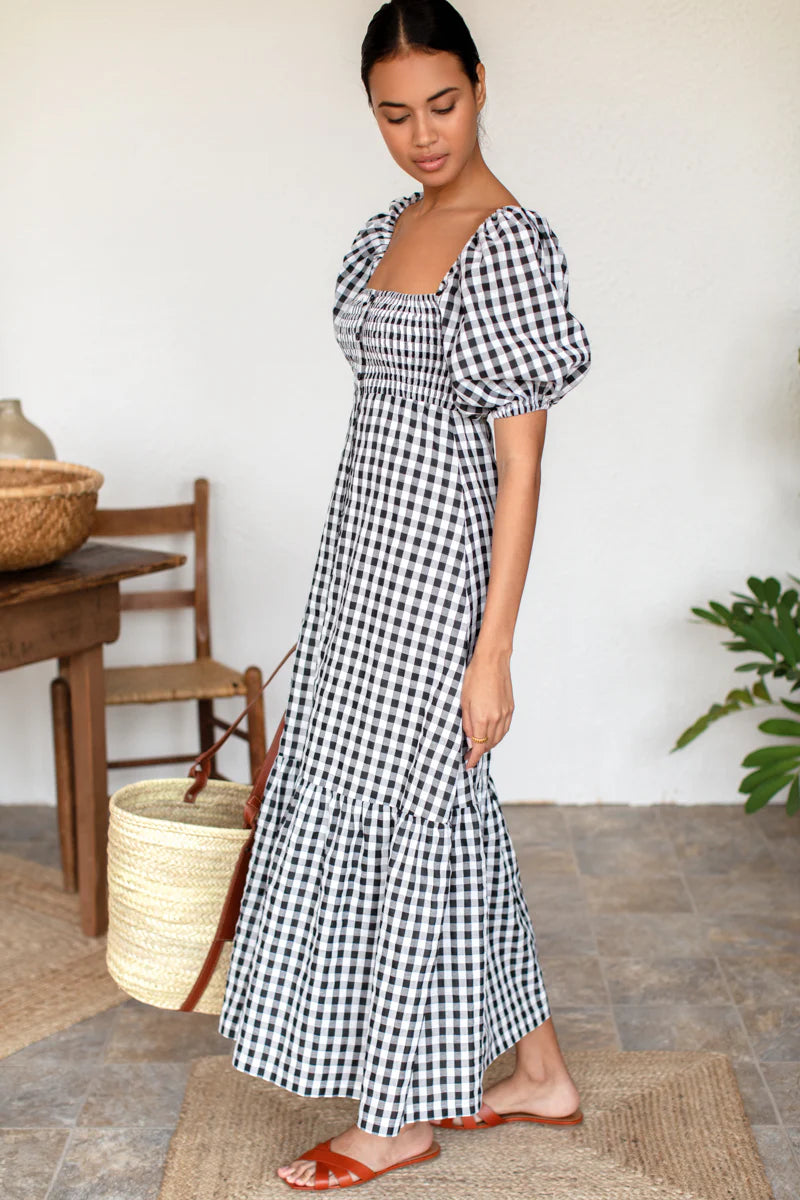 Image of model wearing Emerson Fry Love Tomas Santiago Maxi Dress in Black + White Gingham Check. Santiago dress has a square neckline, shirred bodice, short puff sleeve, and full length skirt with button front closure.