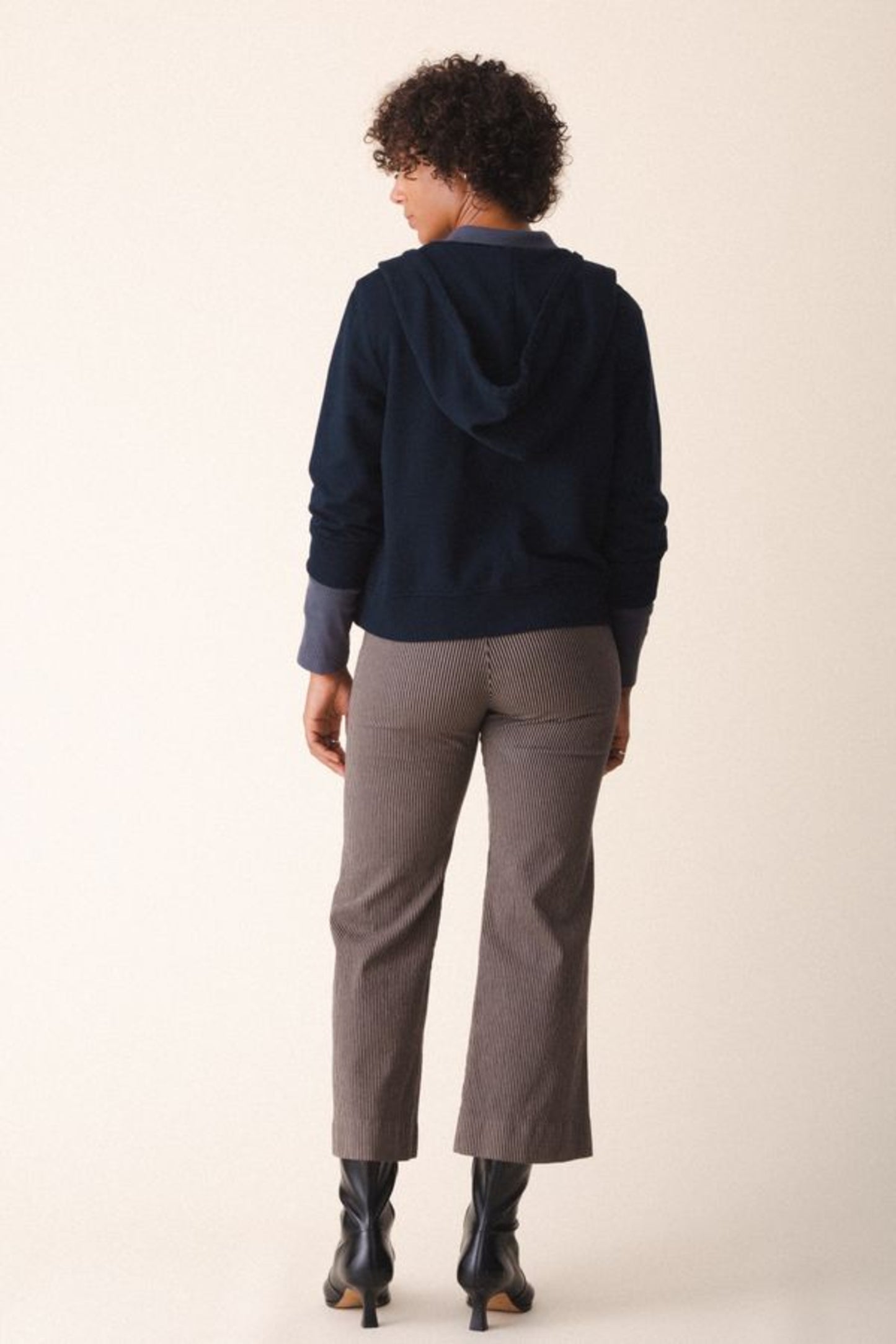 Image of model wearing Prairie Underground Simple Life Hoodie in Midnight Navy Blue. Simple Life is a slightly cropped zip front hoodie sweatshirt made from an organic cotton fleece. Designed and produced in Seattle, Washington.