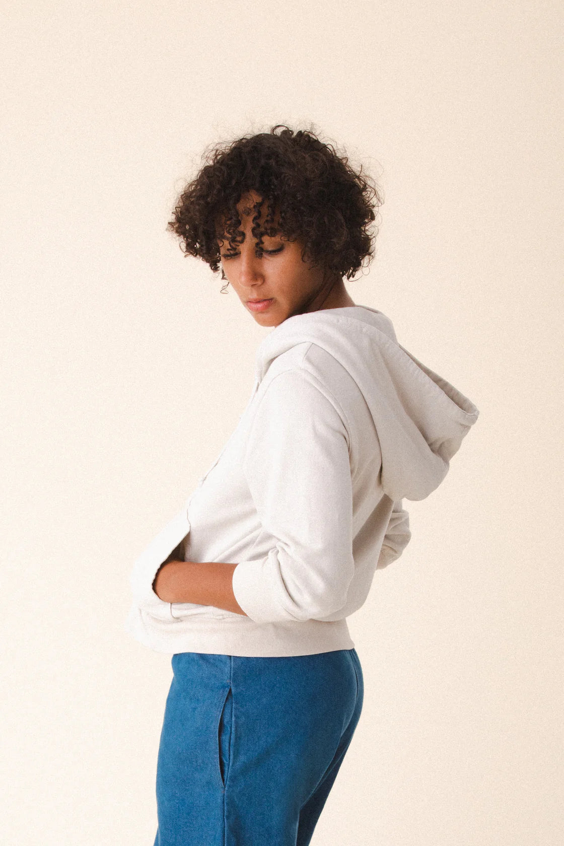 Image of model wearing Prairie Underground Simple Life Hoodie in Oyster White. Simple Life is a slightly cropped zip front hoodie sweatshirt made from an organic cotton fleece. Designed and produced in Seattle, Washington.