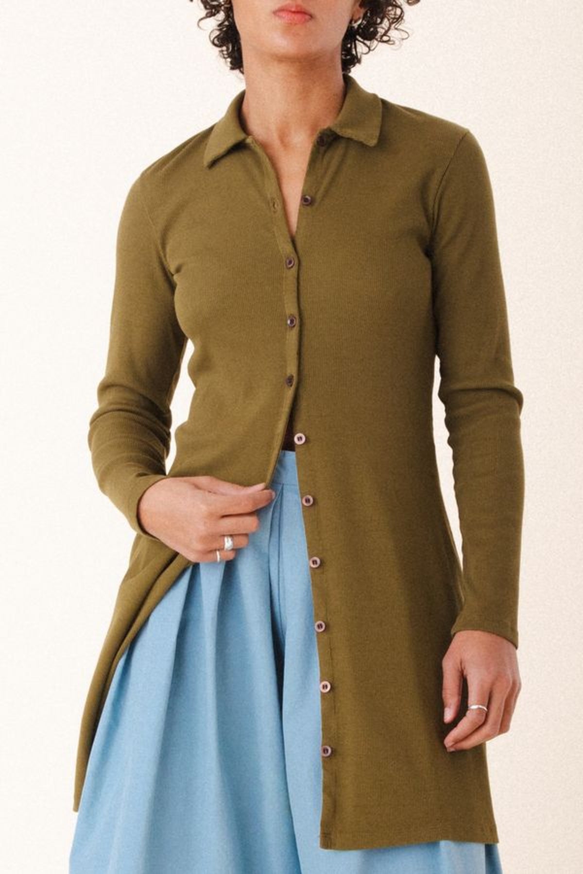 Image of model wearing Cavalos Shirt Dress in Herb Green Rib. Cavalos is a fitted shirt dess with a classic collar that hits mid-thigh made from organic cotton Ribbed fabric.