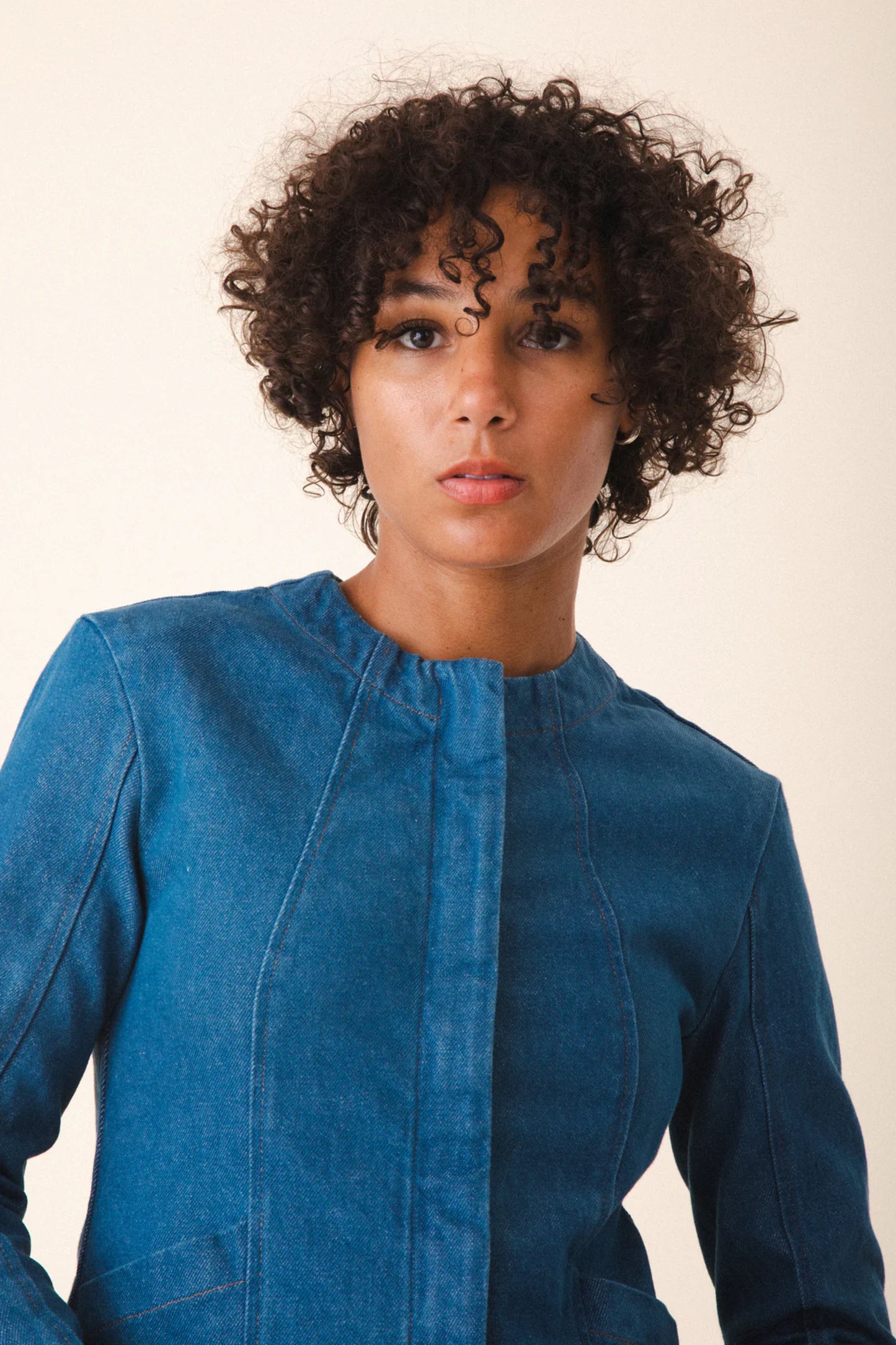 Image of model wearing Prairie Underground Dune Tailored Jean Jacket. Dune Jacket is a tailored collarless jacket with a hidden zip front closure. Designed and produced in Seattle, Washington.