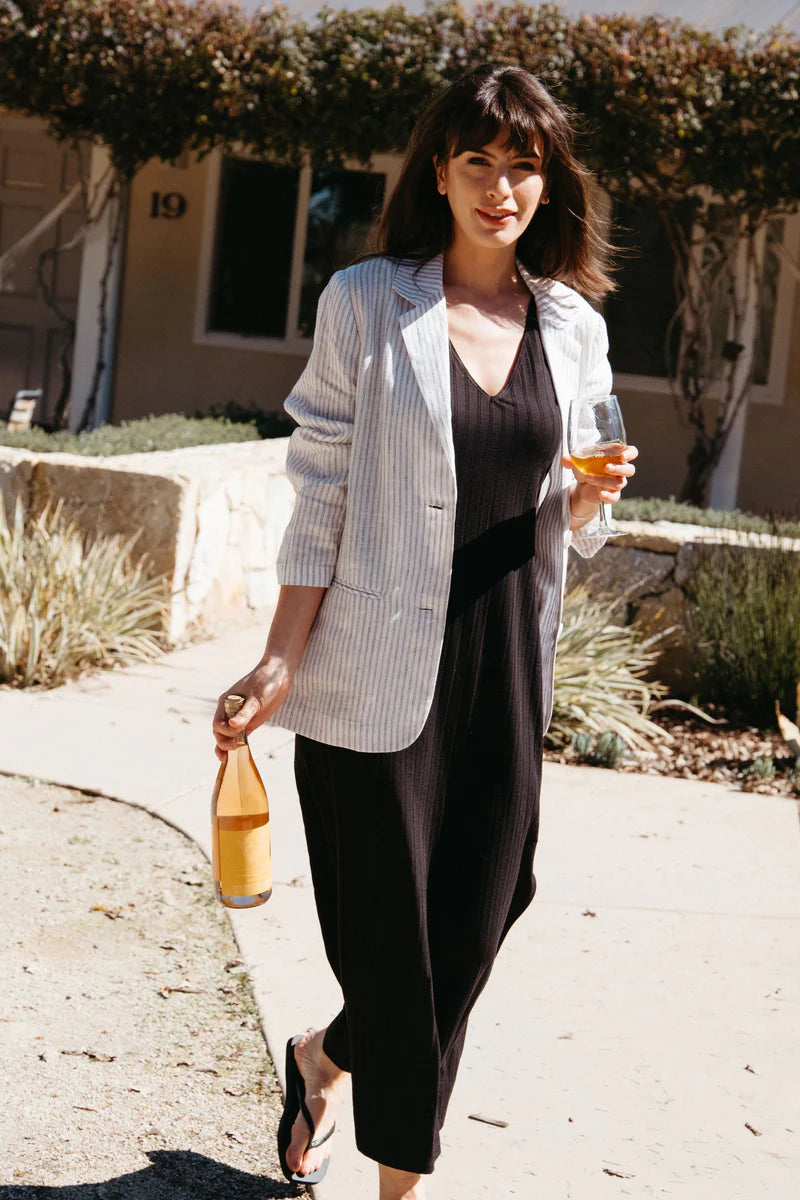 Image of model wearing Whimsy + Row Ava Reversible Column Dress in Black Eco-Rib. Ava Dress has a v-neck or high neck open and can be worn front to back. Full length with symmetrical side slits at hem. Sleeveless. Made in Los Angeles.