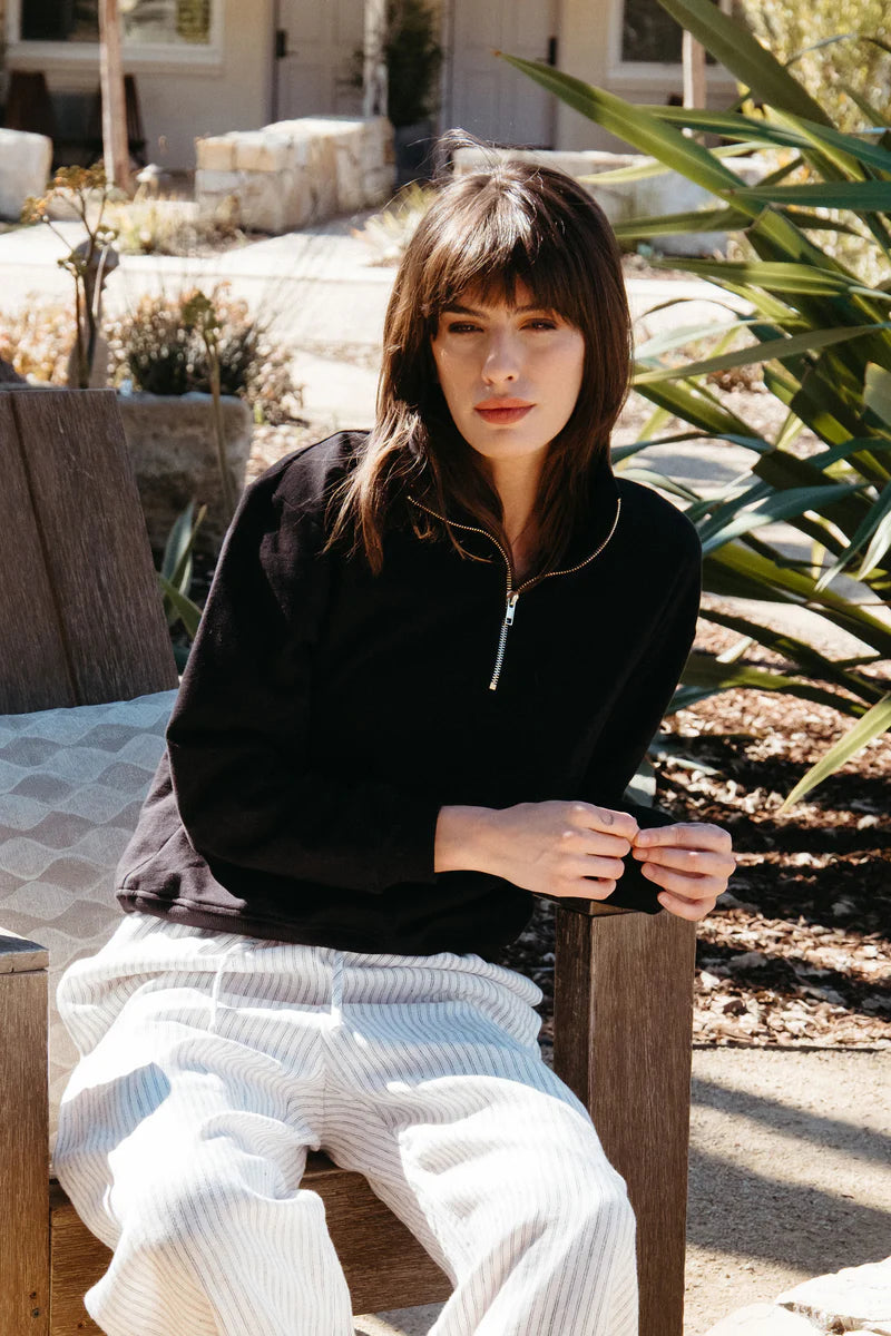 Image of model wearing Whimsy + Row Diana Half Zip Pullover in Black. Made in USA from organic cotton fleece.