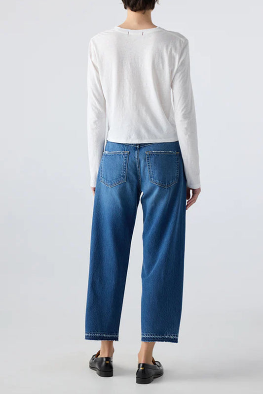 Image of model wearing AMO Denim Maria Barrel Jean in Long Weekend Wash. Maria is a cropped, raw hem Jean with a twisted seam giving a barrel leg silhouette. Made in USA.