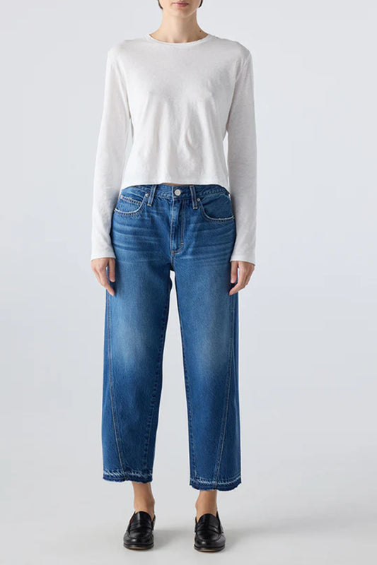 Image of model wearing AMO Denim Maria Barrel Jean in Long Weekend Wash. Maria is a cropped, raw hem Jean with a twisted seam giving a barrel leg silhouette. Made in USA.