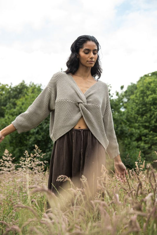 Image of model wearing Beaumont Organic Brooke Leigh Reversible Open Back Sweater in Natural Beige. Brook Leigh is a medium length, long sleeve sweater with a twist knot detail on one side and boat neck finish on the other side. Ethically made in Portugal from recycled Cotton yarns.