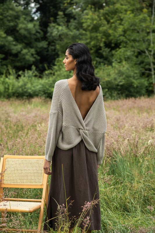 Image of model wearing Beaumont Organic Brooke Leigh Reversible Open Back Sweater in Natural Beige. Brook Leigh is a medium length, long sleeve sweater with a twist knot detail on one side and boat neck finish on the other side. Ethically made in Portugal from recycled Cotton yarns.