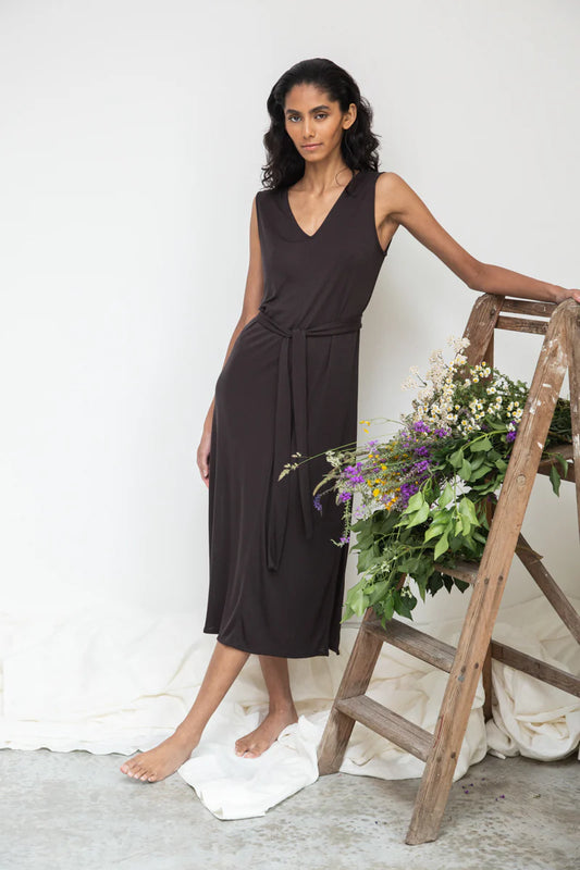 Image of model wearing Beaumont Organic Catalina Lou Column Dress in Charcoal Lyocell. Catalina Dress has a v-neck front and v-back with a midi length and symmetrical side slits; optional waist sash. Ethically made in Portugal.