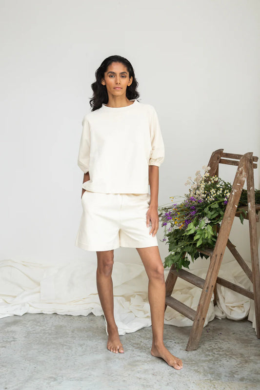Image of model wearing Beaumont Organic Sylvia Lounge Short in Un-Dyed Felpe Cotton. Sylvia is a relaxed fitting pull-on lounge short that hits mid-knee length. Ethically made in Portugal from organic Cotton.