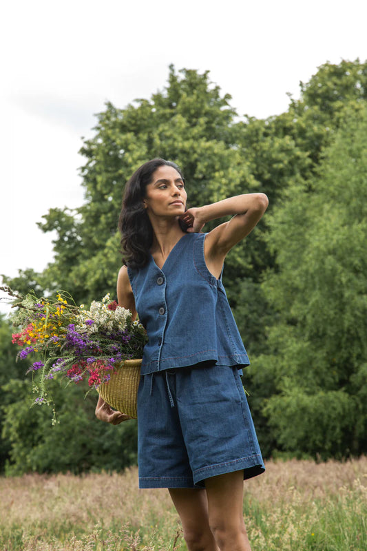 Image of model wearing Beaumont Organic Jovie Leigh Denim Vest. Jovie Leigh features a swinging body, pleated undersleeve, and two tonal buttons on front. Ethically made in Portugal from organic cotton denim.