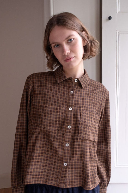 Image of model wearing BIBICO Fair Trade Clothing Ada Button Down Blouse in Rust Check Flannel. 