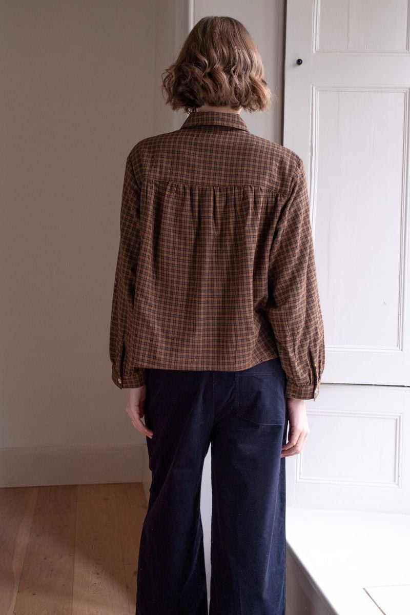 Image of model wearing BIBICO Fair Trade Clothing Ada Button Down Blouse in Rust Check Flannel. 