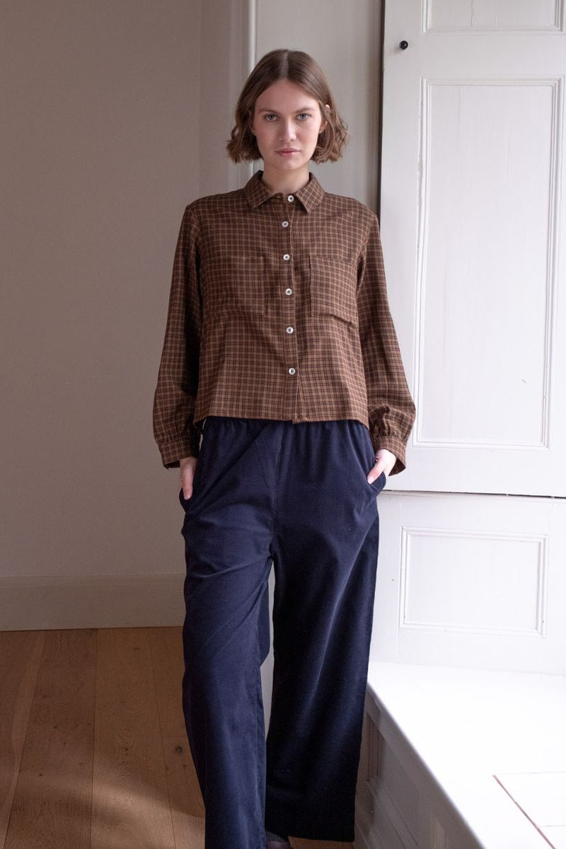 Image of model wearing BIBICO Fair Trade Clothing Ada Button Down Blouse in Rust Check Flannel. 