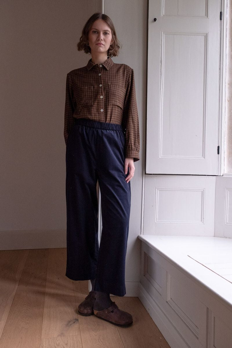 Image of model wearing BIBICO Fair Trade Clothing Ada Button Down Blouse in Rust Check Flannel. 