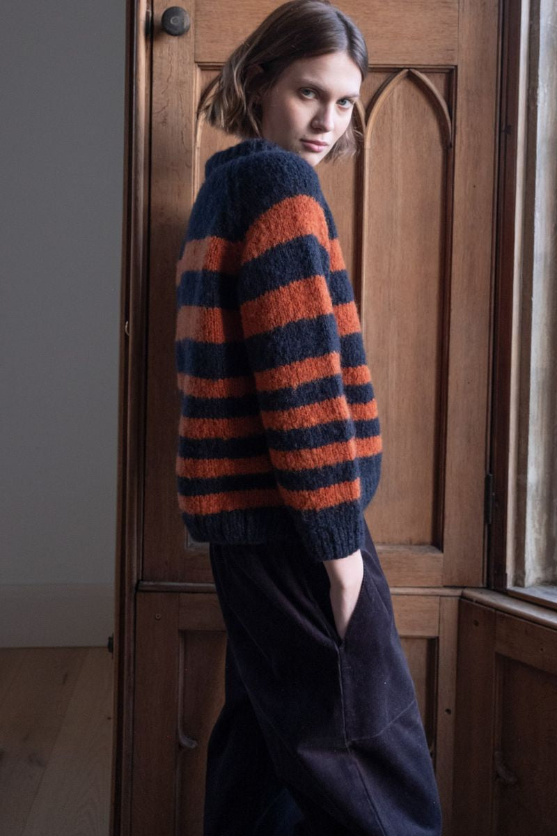 Image of model wearing BIBICO Fair Trade Clothing Force 5 Mohair Sweater in Navy Pumpkin Wide Stripe. 