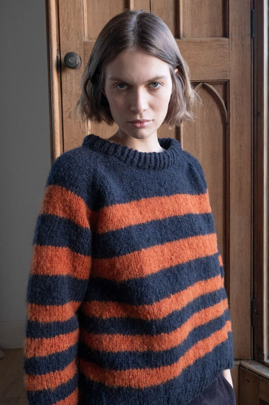 Image of model wearing BIBICO Fair Trade Clothing Force 5 Mohair Sweater in Navy Pumpkin Wide Stripe. 