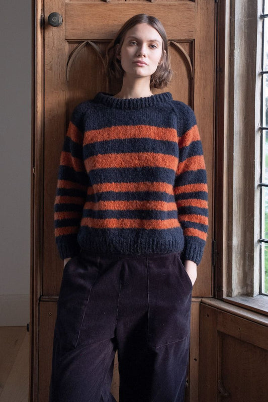 Image of model wearing BIBICO Fair Trade Clothing Force 5 Mohair Sweater in Navy Pumpkin Wide Stripe. 