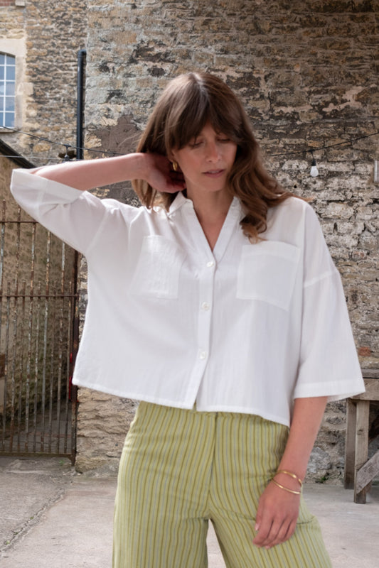 Image of model wearing BIBICO Ava Oversized Button Down in White Stripe Cotton. Ava is a boxy fitting button down with an open neckline and elbow length sleeve. Produced by Fair Trade Certified makers using organic cotton.  