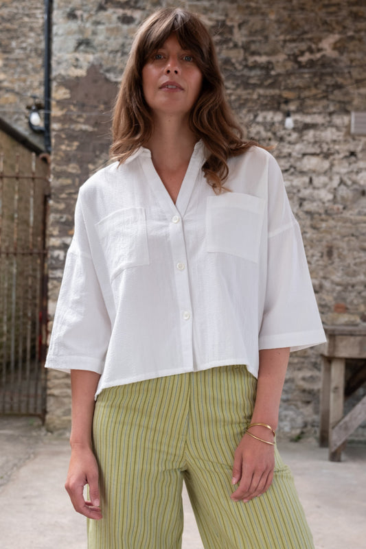 Image of model wearing BIBICO Ava Oversized Button Down in White Stripe Cotton. Ava is a boxy fitting button down with an open neckline and elbow length sleeve. Produced by Fair Trade Certified makers using organic cotton.  