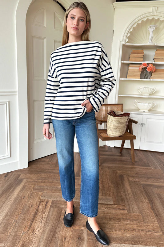 Image of model wearing Emerson Fry Bateau Top in Navy Stripe. Bateau top is a cotton rib boatneck top with dropped shoulder and boxy body in a classic white and navy blue stripe. 