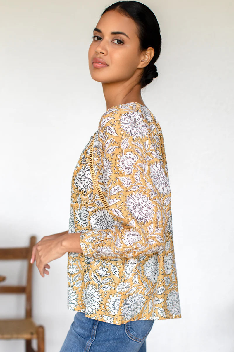 Image of model wearing Emerson Fry (Love Thomas) Lucy Heirloom Blouse. Lucy Heirloom Blouse is a peasant style blouse with button front details and frills along hem. Offered in sustainable modal with a hand block printed white floral pattern on soft yellow.