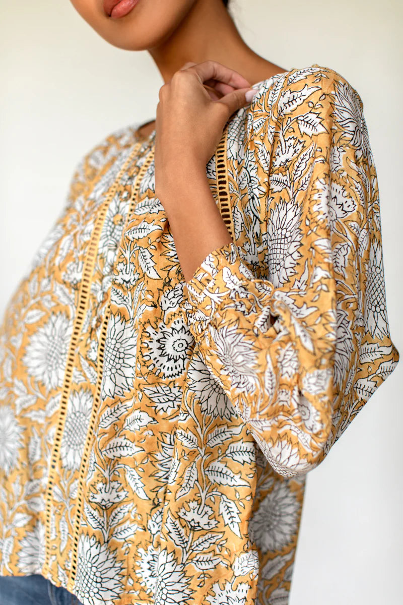 Image of model wearing Emerson Fry (Love Thomas) Lucy Heirloom Blouse. Lucy Heirloom Blouse is a peasant style blouse with button front details and frills along hem. Offered in sustainable modal with a hand block printed white floral pattern on soft yellow.