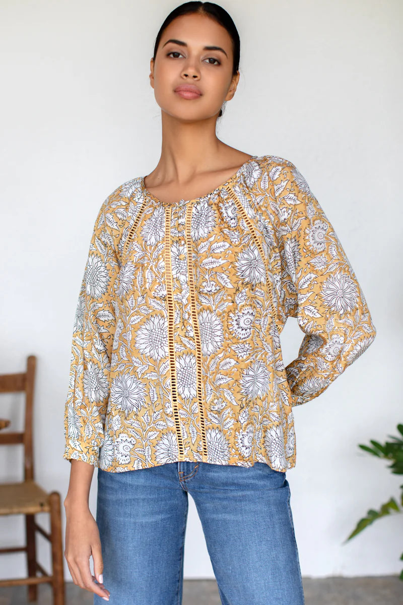 Image of model wearing Emerson Fry (Love Thomas) Lucy Heirloom Blouse. Lucy Heirloom Blouse is a peasant style blouse with button front details and frills along hem. Offered in sustainable modal with a hand block printed white floral pattern on soft yellow.