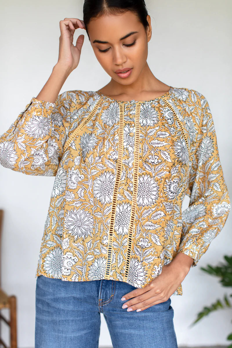 Image of model wearing Emerson Fry (Love Thomas) Lucy Heirloom Blouse. Lucy Heirloom Blouse is a peasant style blouse with button front details and frills along hem. Offered in sustainable modal with a hand block printed white floral pattern on soft yellow.