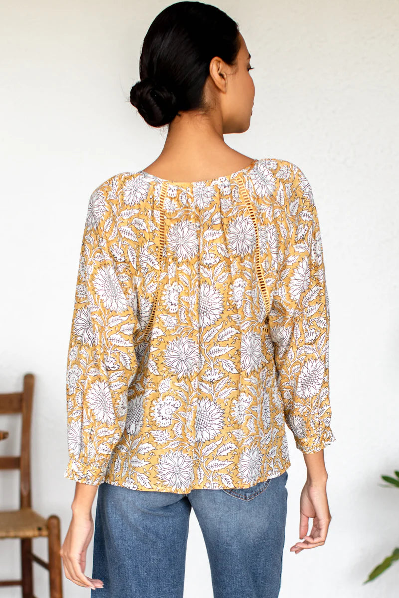 Image of model wearing Emerson Fry (Love Thomas) Lucy Heirloom Blouse. Lucy Heirloom Blouse is a peasant style blouse with button front details and frills along hem. Offered in sustainable modal with a hand block printed white floral pattern on soft yellow.