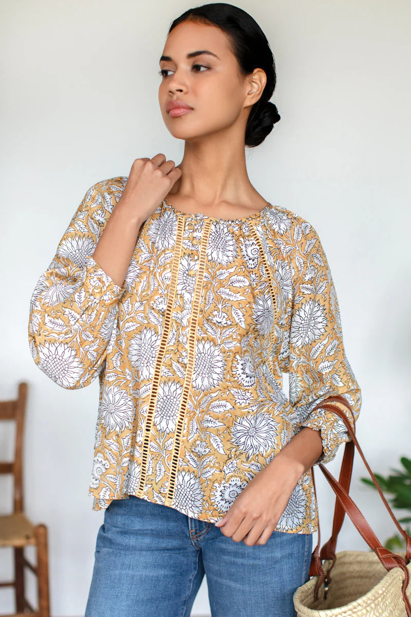 Image of model wearing Emerson Fry (Love Thomas) Lucy Heirloom Blouse. Lucy Heirloom Blouse is a peasant style blouse with button front details and frills along hem. Offered in sustainable modal with a hand block printed white floral pattern on soft yellow.