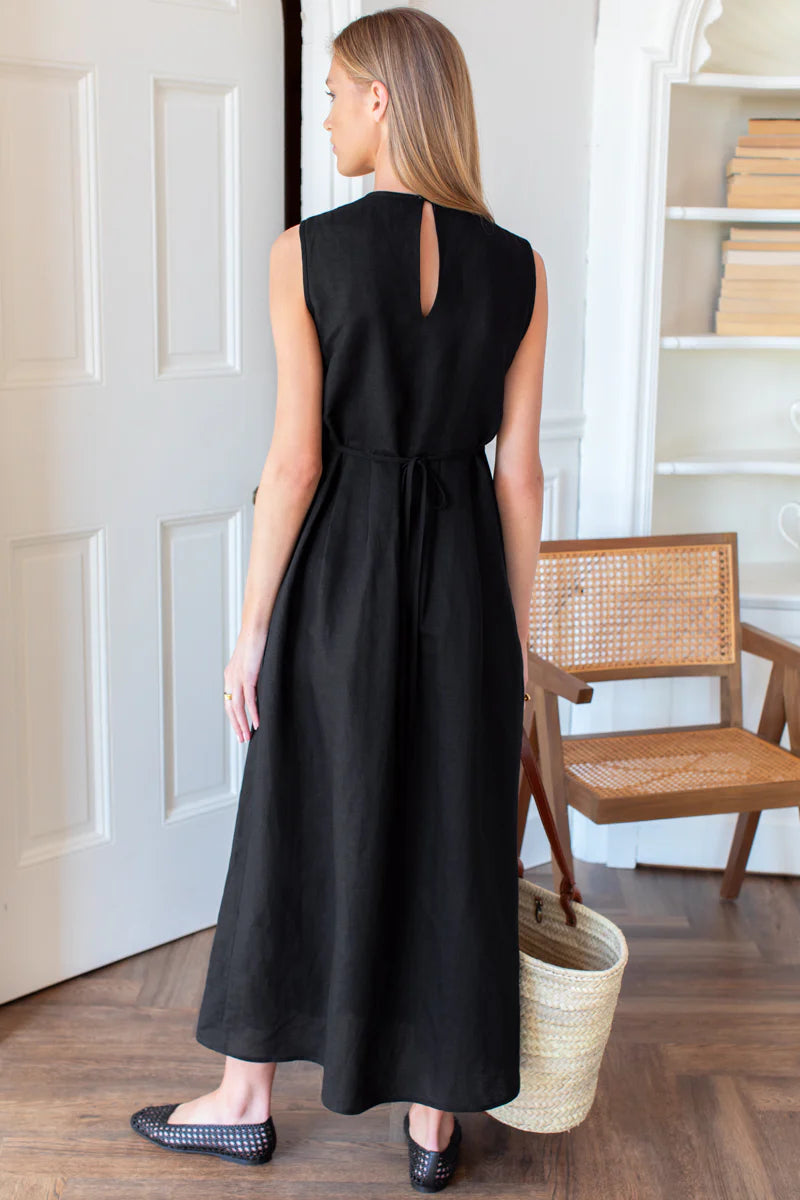 Image of model wearing Emerson Fry Plait Maxi Dress in Black Viscose Linen. Plait Dress is a sleeveless summer dress with front pleat details on the body, cinched waistline, and a-line style maxi skirt.