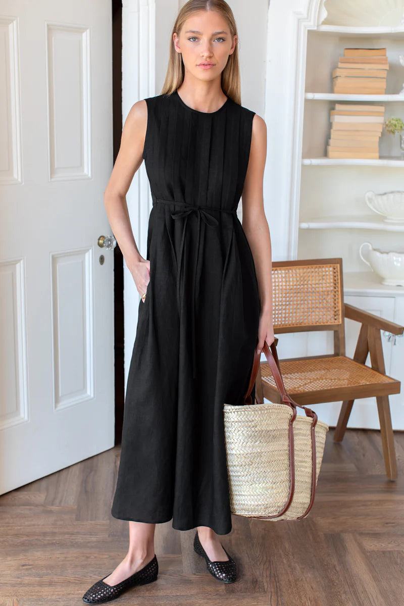 Image of model wearing Emerson Fry Plait Maxi Dress in Black Viscose Linen. Plait Dress is a sleeveless summer dress with front pleat details on the body, cinched waistline, and a-line style maxi skirt.