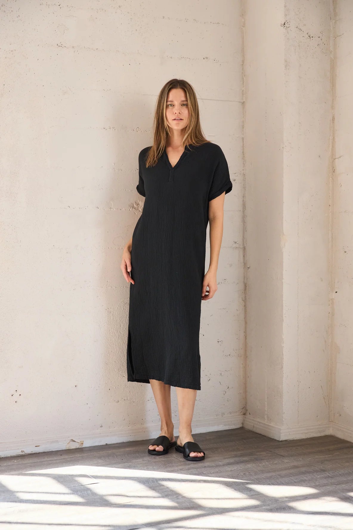 Image of IT IS WELL LA Mandarin Gauze Midi Dress in Black. This loose fitting dress is made from an organic cotton crinkled Gauze, hits midi length with symmetrical side slits, rolled short sleeve, and open Mandarin collar. Made in USA. 
