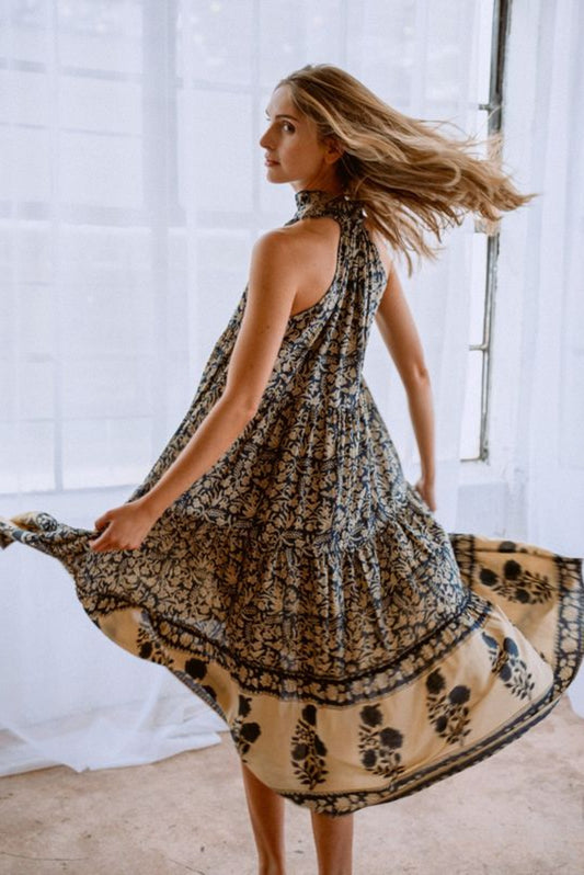 Image of model wearing MAELU DESIGNS Poppy Tiered Sundress. Poppy dress is a halter style sundress with flowing, tiered a line skirt, v-neck opening, and frilled bodice in a hand block printed Delia Floral Printed Modal.