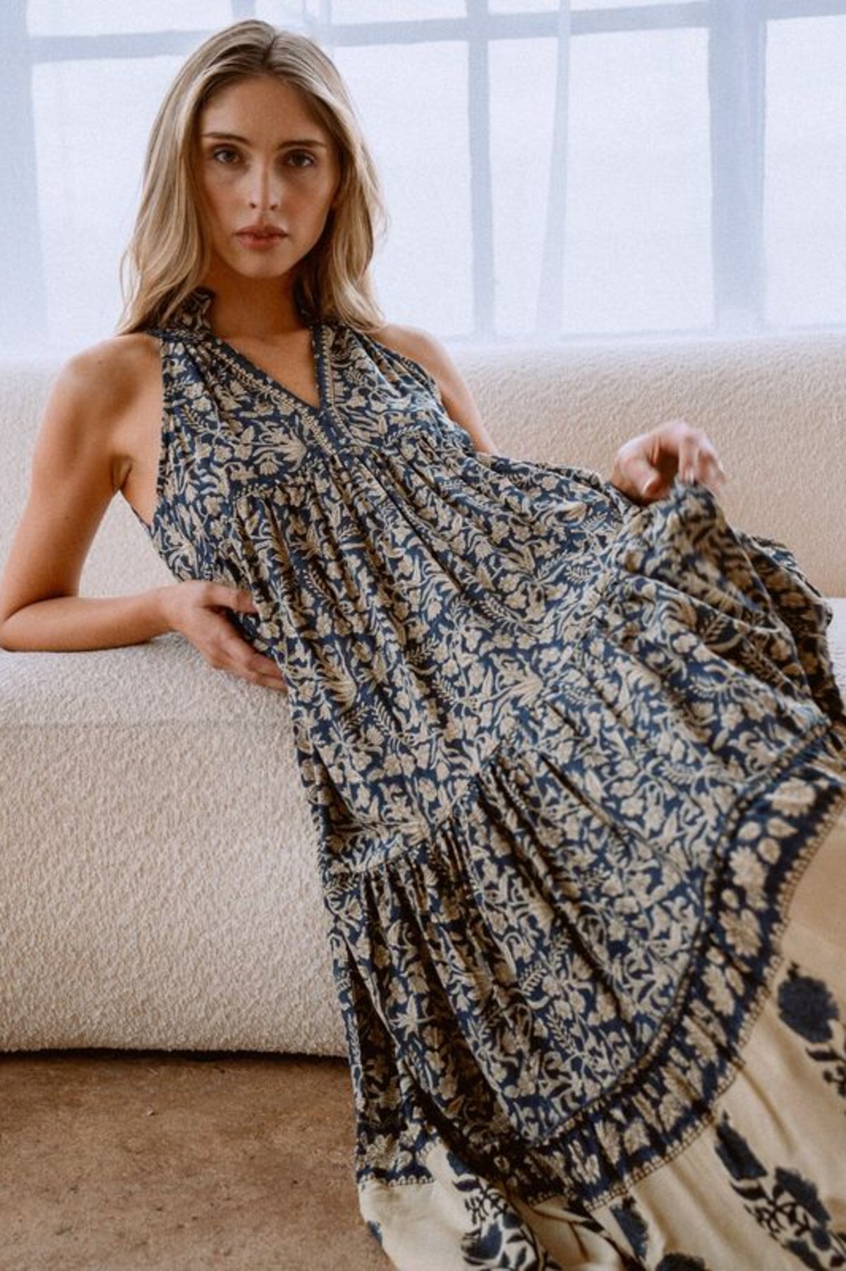 Image of model wearing MAELU DESIGNS Poppy Tiered Sundress. Poppy dress is a halter style sundress with flowing, tiered a line skirt, v-neck opening, and frilled bodice in a hand block printed Delia Floral Printed Modal. 